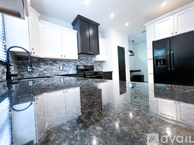 A kitchen with black and white cabinets and a marble countertop.