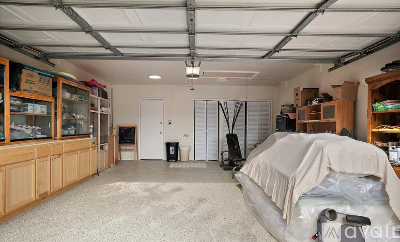 A spacious garage with a car covered in a tarp on the right side.
