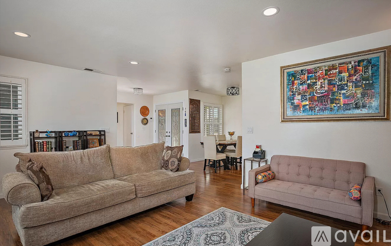 A living room with a couch, a chair, and a painting on the wall.