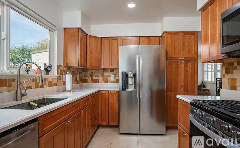 A kitchen with wooden cabinets and a stainless steel refrigerator.