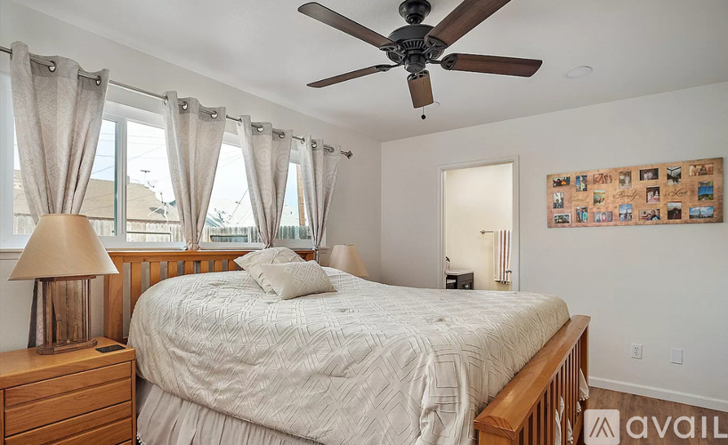 A bedroom with a bed, a ceiling fan, and a window with curtains.