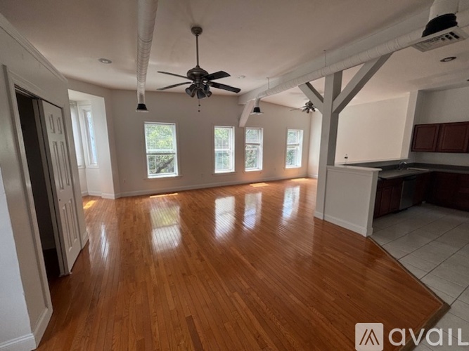 A spacious room with wooden floors and a ceiling fan.