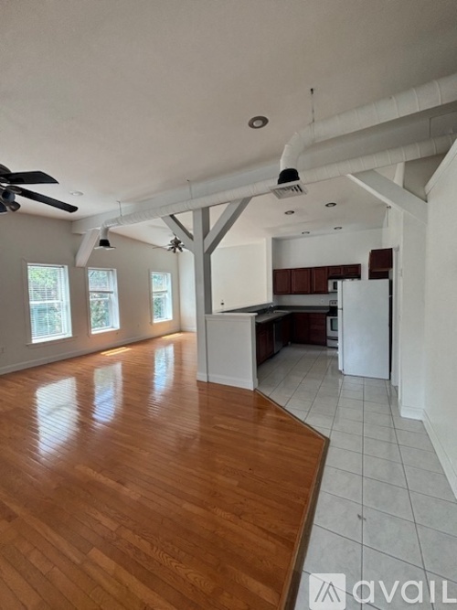 A spacious kitchen and living room with hardwood floors and white walls.