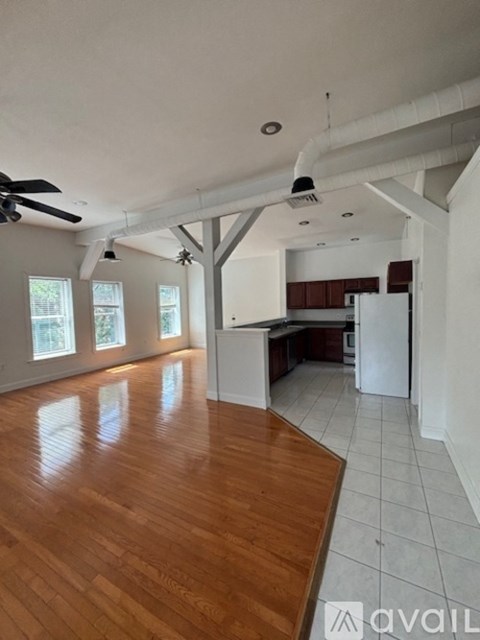 A spacious kitchen and living room with hardwood floors and white walls.