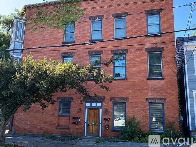 A red brick building with a tree in front of it.
