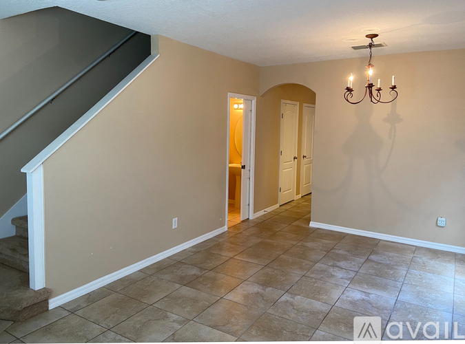 A room with a chandelier and a doorway leading to another room.