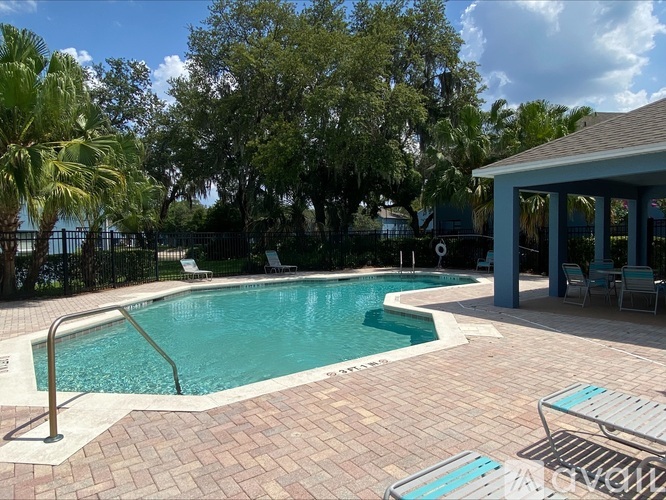 A pool surrounded by a brick patio and palm trees.