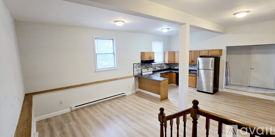 A large open living space with a kitchen area and a refrigerator.