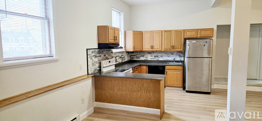 A kitchen with wooden cabinets and a stainless steel refrigerator.