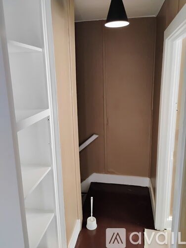 A small, dark room with a white door and a brown floor.