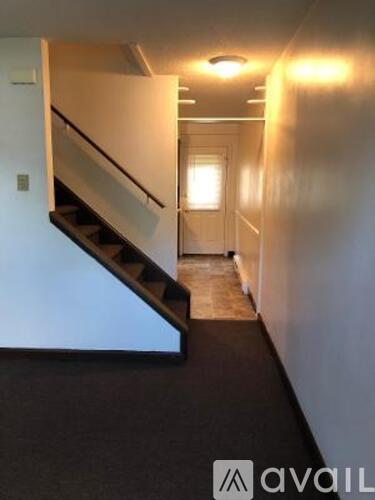 A hallway with a staircase and a light on the wall.