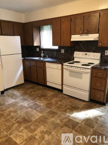 A kitchen with a white fridge, white stove, and brown cabinets.
