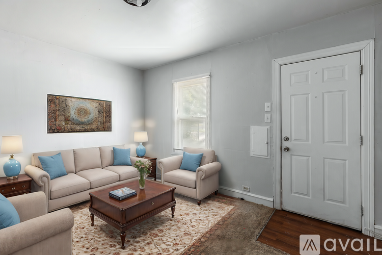 A living room with a couch, chairs, and a rug.
