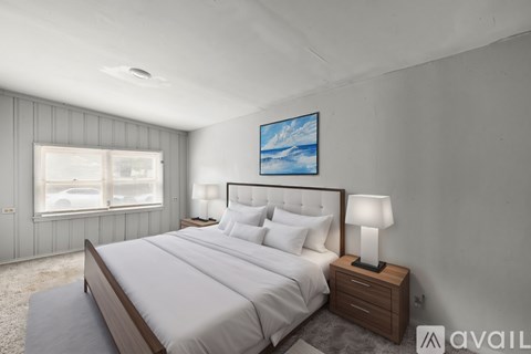 A bedroom with a large bed, a nightstand with a lamp, and a painting on the wall.