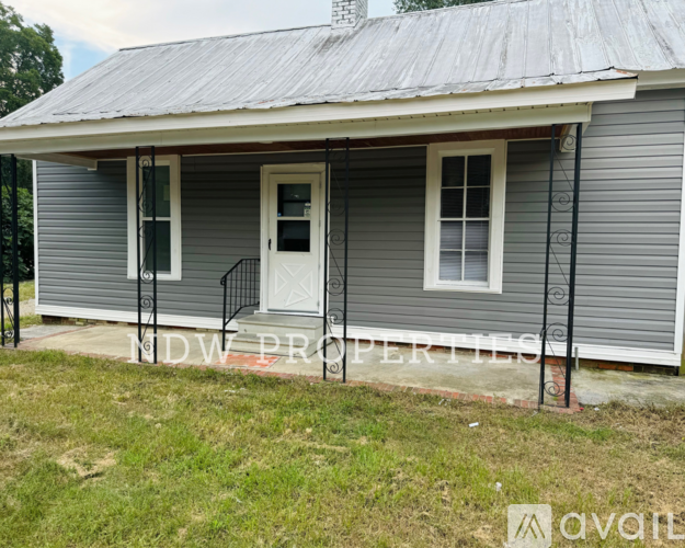 A house with a grey siding and a white door is for sale.
