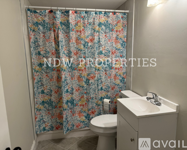 A bathroom with a floral shower curtain and a white sink.