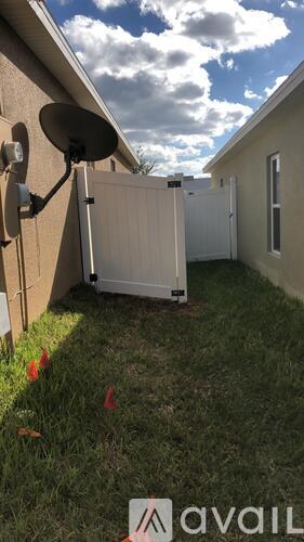A satellite dish is mounted on a house and a white refrigerator is outside.