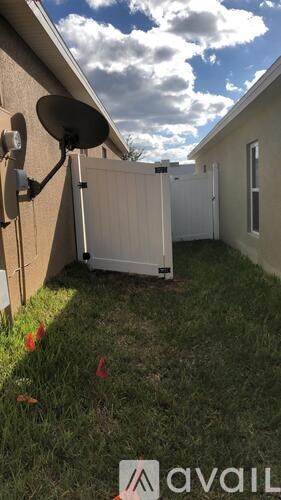 A satellite dish is mounted on a house and a white refrigerator is outside.