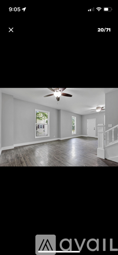 A room with a ceiling fan and a window showing greenery outside.