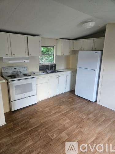A kitchen with white appliances and wooden floors.