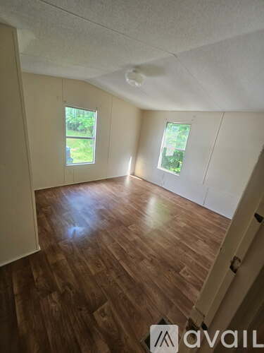 A room with wooden floors and two windows.