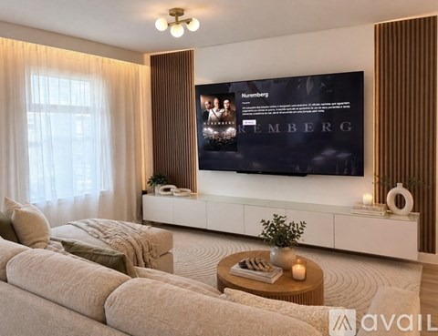 A modern living room with a large screen displaying the word "NEMBERG" and a small table with a plant and candles.