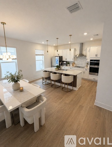 A modern kitchen with white cabinets and a wooden floor.