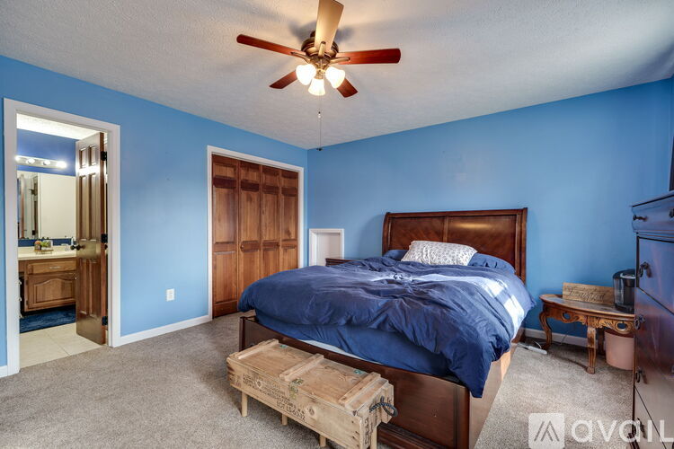 A bedroom with blue walls and a bed with a wooden headboard.