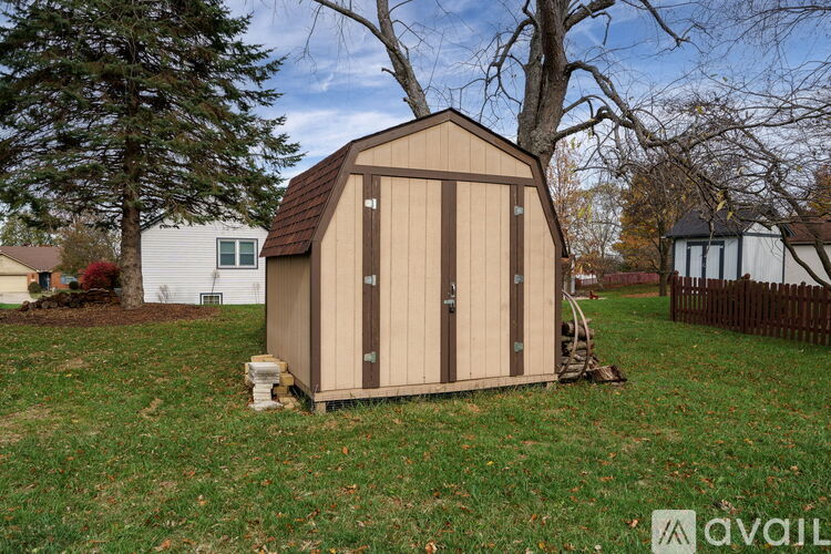 A small wooden shed sits in a grassy yard.