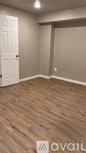 A room with a white door and wooden flooring.