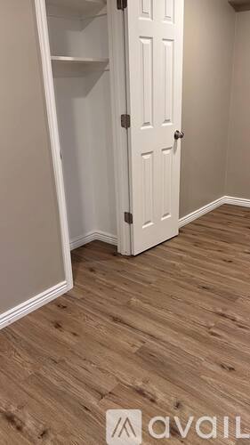 A white door is in a room with wooden flooring.