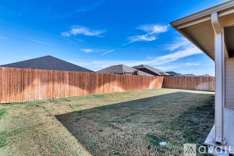 A backyard with a wooden fence and a house.