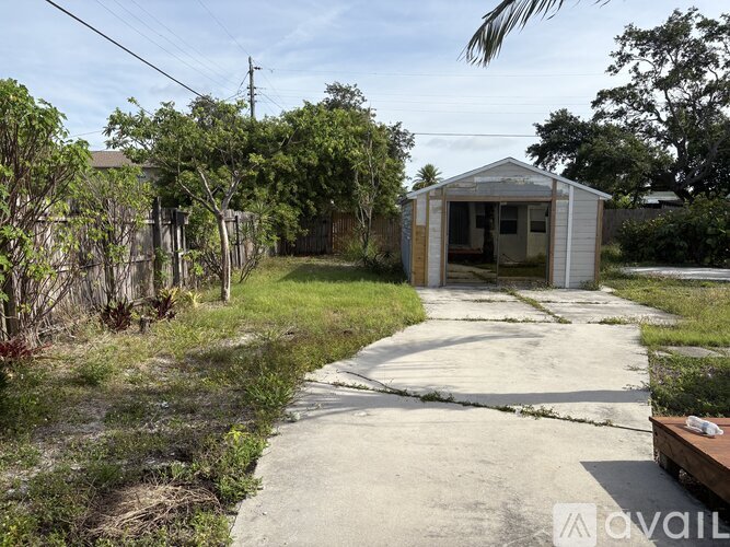 A small building sits in the middle of a grassy area with a concrete path leading to it.