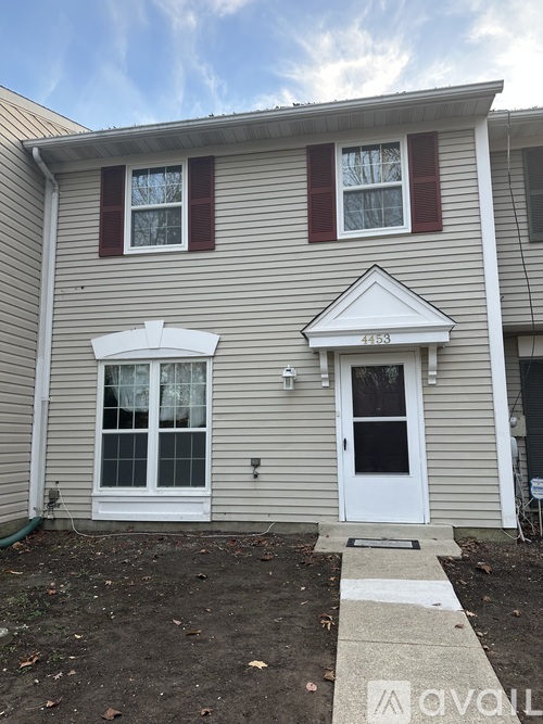 A house with a white door and windows with red shutters.