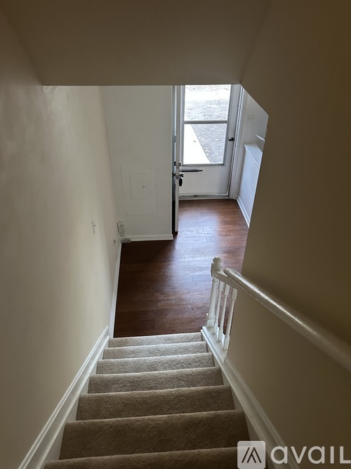 A staircase with a beige carpeted runner and white balusters leads to a doorway.