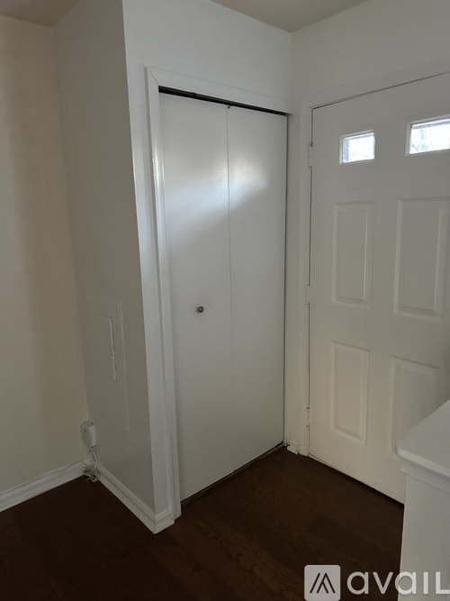 A white door is in a room with wooden floors and white walls.