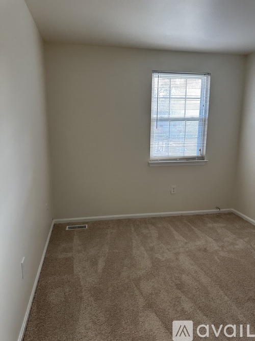 A room with a carpeted floor and a window with blinds.