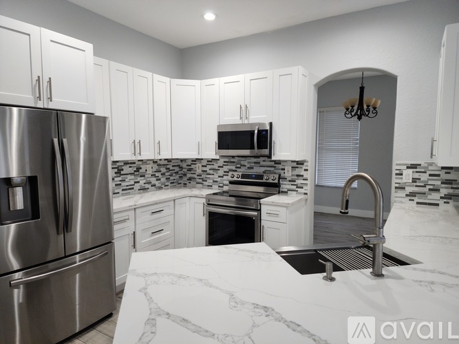 A kitchen with white cabinets and a marble countertop.