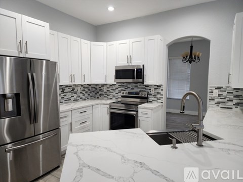 A kitchen with white cabinets and a marble countertop.