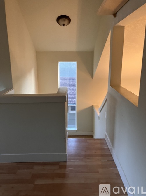 A hallway with wooden floors and white walls.