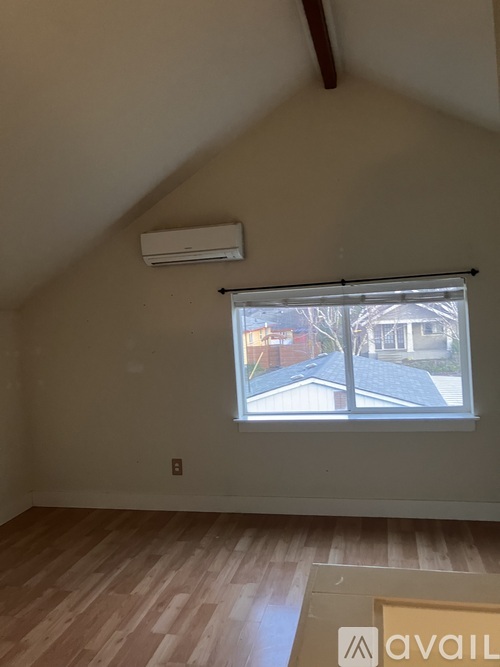 A room with a window and a wooden floor.