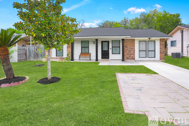 A house with a white fence and a tree in front of it.