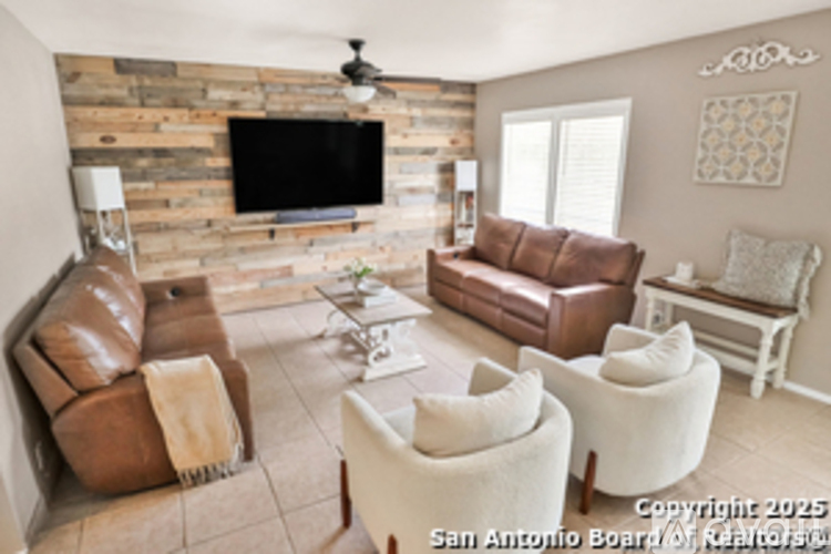 A living room with a stone wall and a flat screen TV.