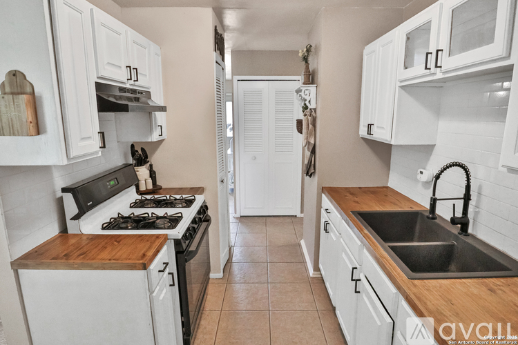 A kitchen with white cabinets and a wooden island.