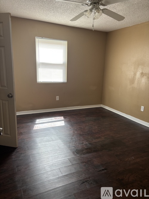 A room with a ceiling fan and a window letting in sunlight.