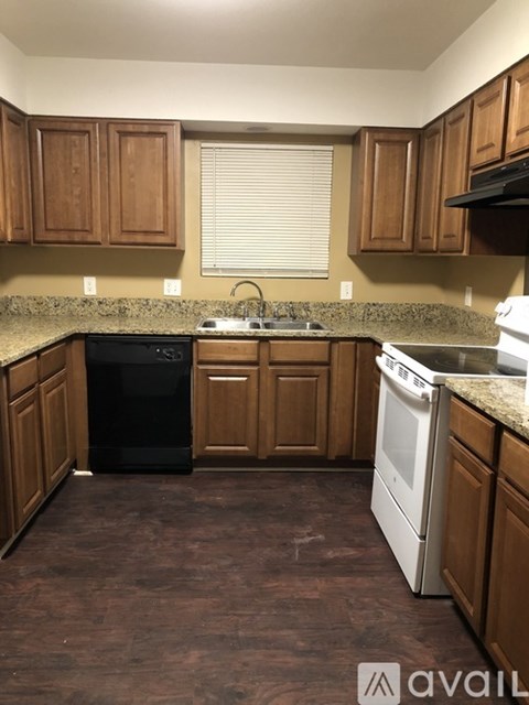 A kitchen with brown cabinets and a black dishwasher.
