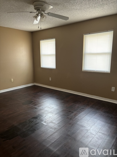 A room with a ceiling fan and two windows.