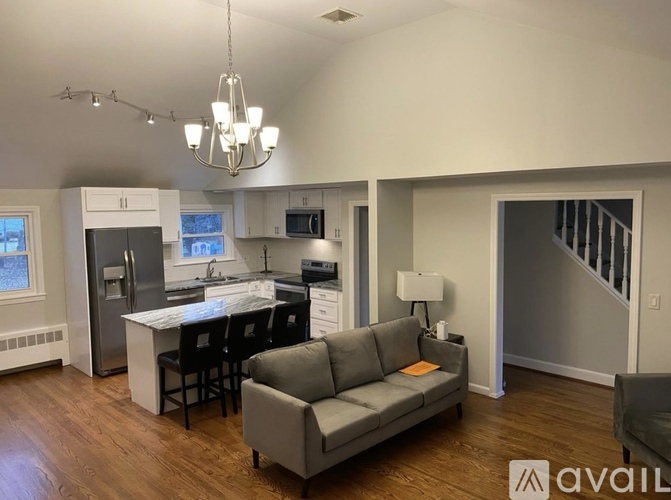 A modern kitchen with a dining table and a grey sofa.
