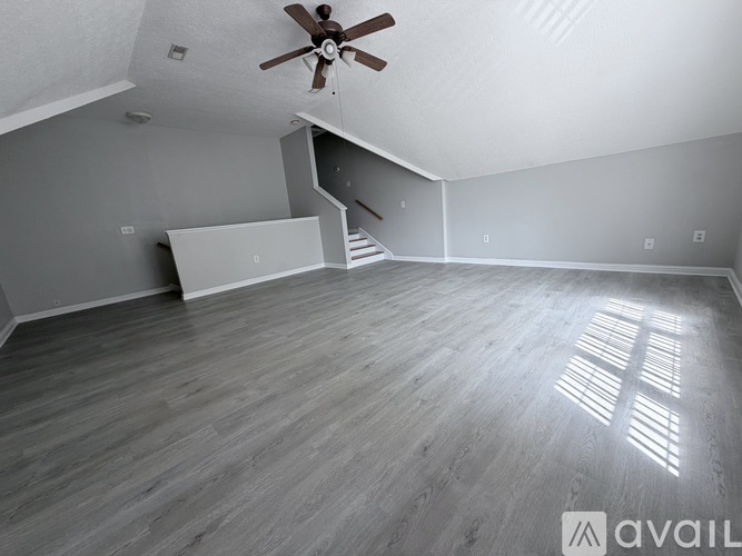 A spacious room with a ceiling fan and wooden flooring.