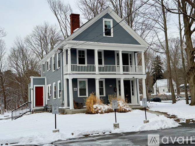 A house with a red door and a balcony is surrounded by snow.